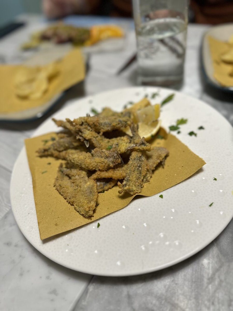 Un piatto di alici fritte impanate, con uno spicchio di limone e prezzemolo.