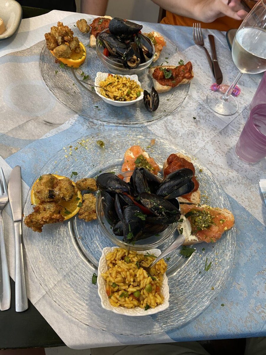 Antipasto di mare servito nel piatto: cozze, crostini, riso e frittura, su una tavola apparecchiata.